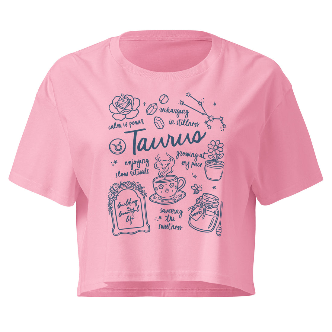 Bubblegum pink Taurus crop top with an indigo journal-style collage of zodiac traits and the bull glyph